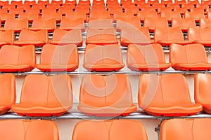 Rows of empty orange plastic grandstand seats at stadium