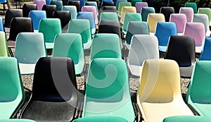 Rows of empty plastic multicolored chairs geometrically arranged under the sun.