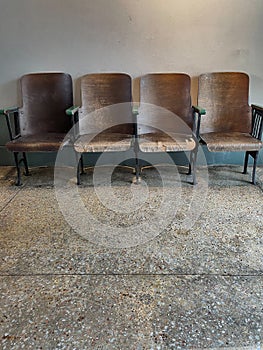 Rows of empty wooden chairs with concrete floor.