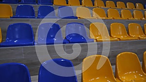 Rows of empty yellow and blue plastic seats on the stadium podium