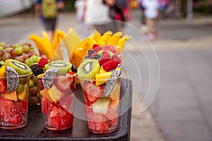 Rows of fresh cut fruit in plastic cups at urban street vendor stand