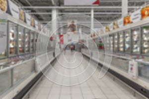 Rows of frozen food refrigeration units in a supermarket. Blurred