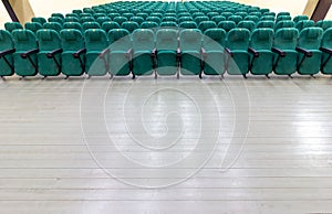 rows of green chairs in the auditorium of a rural cinema or theater.