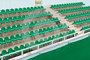 Rows of green spectator seats at sport facility with nobody, diagonal view.