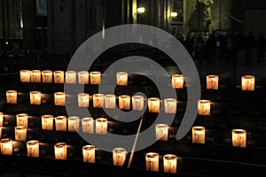 Rows of lit prayer candles in dark church