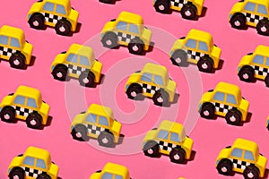 Rows of little yellow toy cabs or taxis on pink