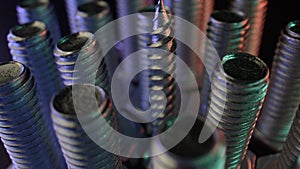 Rows of long bolts and nails on a table with a dark surface. Shiny metal, steel parts for household needs, top view.