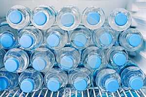 Rows of many transparent plastic bottles with drinking water supply in white refrigerator. Mineral water stack storage in fridge