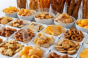 Rows of many types of savory snacks in white ceramic dishes.