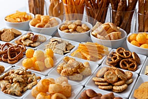 Rows of many types of savory snacks in white ceramic dishes.