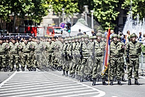 Rows of military troop marching on streets during sunny summer day