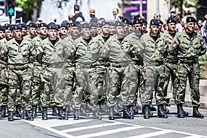 Rows of military troop marching on streets during sunny summer day