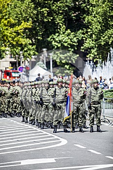 Rows of military troop marching on streets during sunny summer day