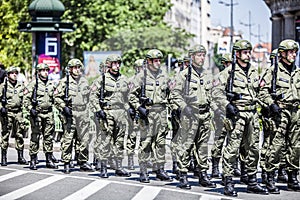 Rows of military troop marching on streets during sunny summer day