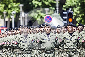 Rows of military troop marching on streets during sunny summer day