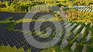 Rows of modern photovoltaic solar panels next to the green field on s summer