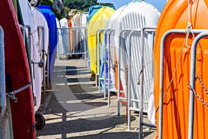 Rows of multicolored dinghies racked vertically in a harbor under a bright sunshine