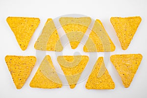 rows of Nachos on a white table. Mexican snack, corn tortilla chips.