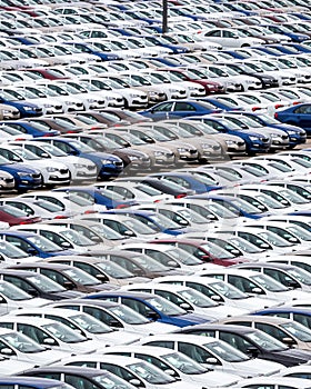 Rows of a new cars parked in a distribution center of a car factory.