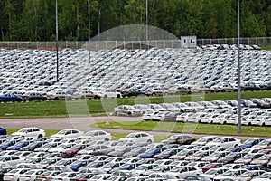 Rows of a new cars parked in a distribution center on a cloudy day in the spring, a car factory