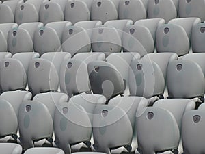 Rows of numbered empty plastic seats at an open-air amphitheater. many audience open theater seats