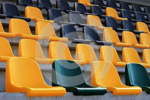 Rows of old plastic black and yellow seats at a stadium