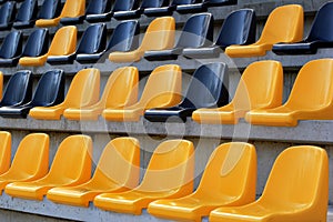 Rows of plastic black and yellow seats at a stadium