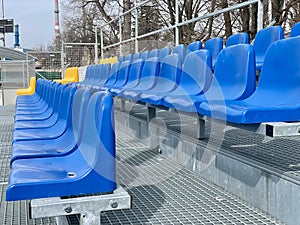 Rows of plastic colorful seats at a stadium. Yellow and blue