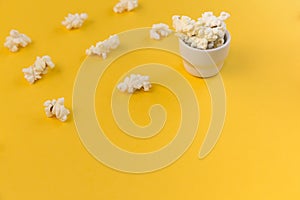 Rows of popcorn and small bowl with popcorn on Yellow background