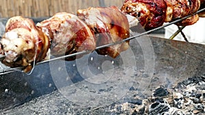 Rows of pork knuckle cooking on a rotisserie