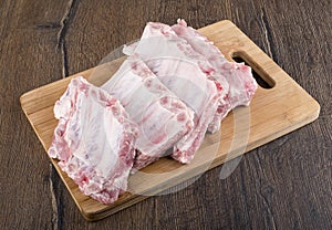 Rows of raw pork ribs on a wooden cutting board