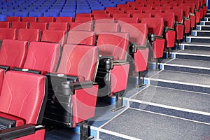 Rows of red and blue seats and stairs in auditorium