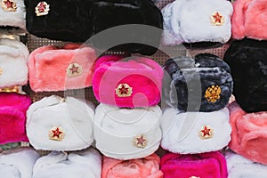 Rows of russian winter hats of different colors with army emblems at the street market iconic popular souvenir from