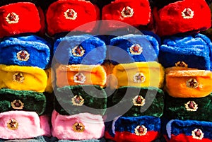 Rows of russian winter hats of different colors with army emblems at the street market at Old Arbat street