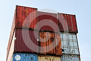 Rows of rusty shipping containers on the background of blue sky