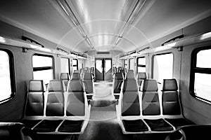 Rows of seats in a passenger railway carriage in monochrome