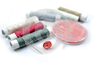 Rows of sewing threads of various colors, sewing needles and shirt buttons