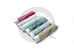 Rows of sewing threads of various colors and sewing needles isolated on white