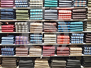 Rows of shirts stacked on parallel shelves in a retail store