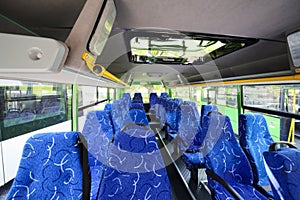 Rows of soft seats inside saloon of empty city bus