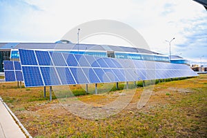 Rows of solar power panels on lawn in big city. Concept for using clean energy and environmental power from sunlight to reduce