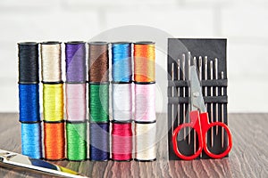 Rows of spools of colorful sewing threads and sew scissors on the table