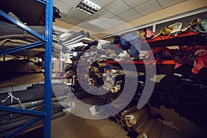 Rows of storage shelves full of fabric and leather rolls at footwear or clothing factory