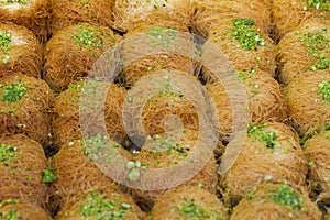 Rows of Sweet Turkish dessert kunefe with pistachio powder, Kataifi pastry, at the market street