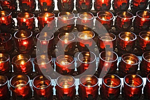 Rows of votive candles in red glass