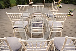 rows of white chairs decorated with flowers at a wedding ceremony in the garden