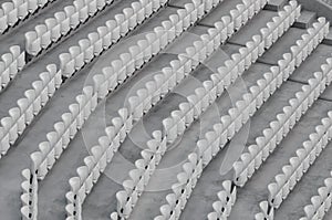 Rows of white empty plastic seats in a stadium.