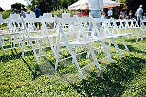 Rows of white folding chairs on lawn