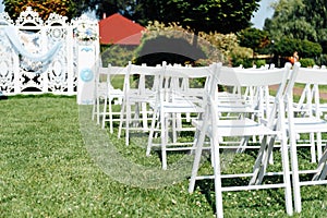 Rows of white folding chairs on lawn