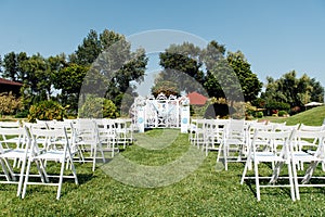 Rows of white folding chairs on lawn